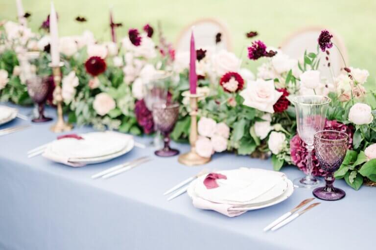 Décoration table d'honneur mariage de Flora & Ivann. Table bleue et compositions florales palette de roses et violet.